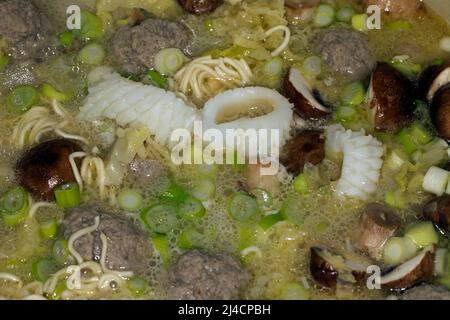 Food photography, Asian soup with squid, mien noodles, cabbage strips, meatballs, spring onion, mushrooms and coconut milk Stock Photo