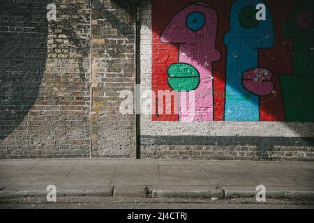 Shoreditch, London, UK - April 14, 2016: Some colourful East London Street Art, caught in some shadow. Stock Photo