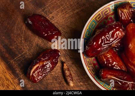 Top view a dry fruits of dates in a ceramic bowl on a wooden board Stock Photo