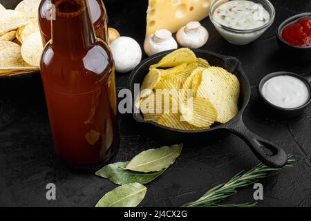 Potato chips. Beer snacks, sauce set, on black stone background Stock Photo