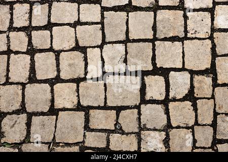 Mosaic of small marble cubes. sidewalks and squares formed by stone carpet with squares. Old cobblestones. High quality photo Stock Photo