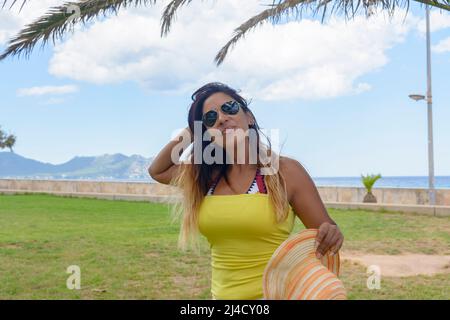 portrait of a latin woman smiling, having fun, on vacation in mallorca posing on a warm spring summer day, under a palm tree, hollidays , Stock Photo