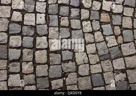 Mosaic of small marble cubes. sidewalks and squares formed by stone carpet with squares. Old cobblestones. High quality photo Stock Photo