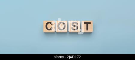 cost word concept from wooden blocks on blue . Cost, expense or company profit and loss concept, cube wooden block with alphabet combine word cost on Stock Photo