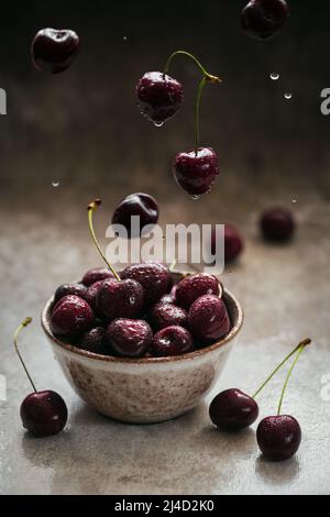 Ripe juicy sweet cherries with water drops in a ceramic bowl Stock Photo