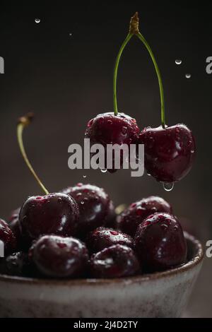 Ripe juicy sweet cherries with water drops in a ceramic bowl Stock Photo