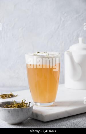Chinese cheese tea with whipped cheese and cream on light gray background. Asian Trendy beverage. Thai milk tea. Vertical format. Close up. Stock Photo