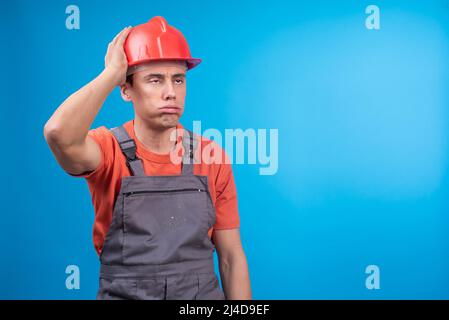Tired male builder in uniform touching hardhat Stock Photo
