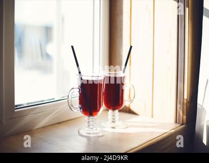 Two glasses of mulled wine on the windowsill overlooking the winter mountains. Winter hot drink Stock Photo