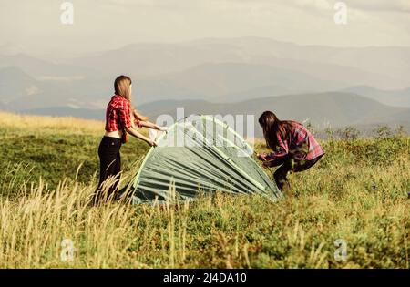 Girls set up tent on top mountain. Camping skills concept. Camping and hiking. In middle of nowhere. Temporary housing. Vacation in mountains. Camping Stock Photo