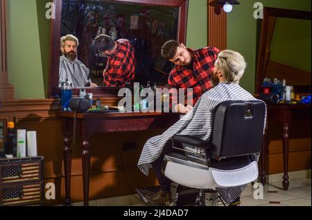 Style in action. professional barber with male client. hipster with dyed beard and moustache. man want new hairstyle. beauty and fashion. mature man Stock Photo
