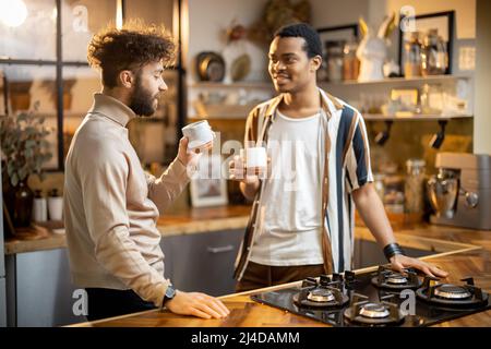 Two men talking and drinking coffee on kitchen at home Stock Photo