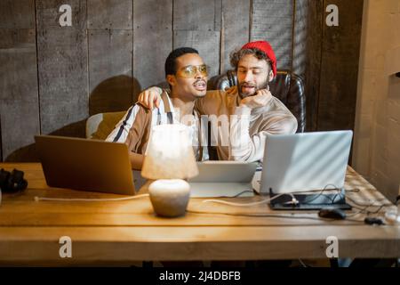 Gay couple working on computers at home office Stock Photo
