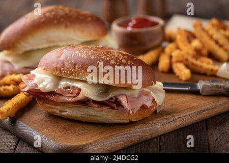 Hot ham and cheese submarine sandwich with french fries on a wooden cutting board Stock Photo