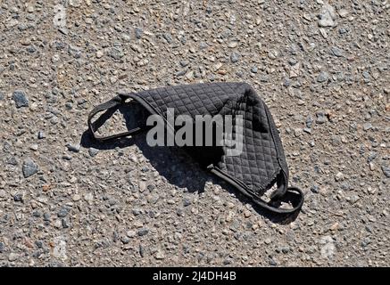 Face mask on floor in street. Improperly discarding used face mask. Stock Photo