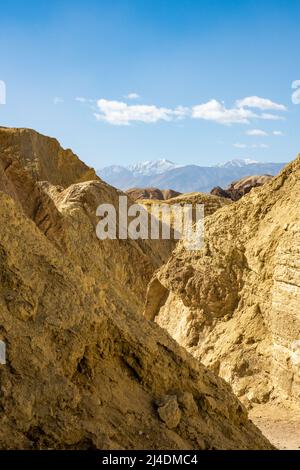 Snow Capped Mountain Stands High Above A Passageway Through Golden Canyon in Death Valley Stock Photo