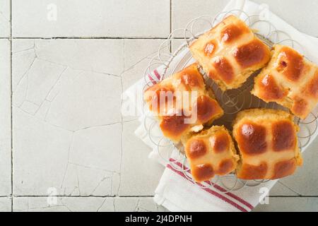 Easter hot cross buns with colored eggs Easter gingerbread rabbits and cookies over light grey old cracked tile table background. Spring holiday bakin Stock Photo