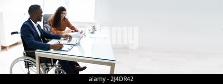 Two Young Businesspeople Working On Laptop At Workplace Stock Photo