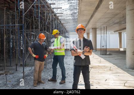 Architect, Engineer, Contractor, or Construction manager holding digital tablet standing with a group of worker at a construction site. Stock Photo