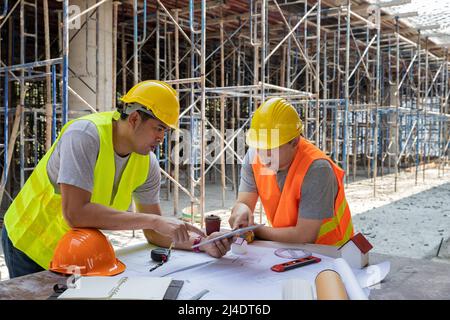 Engineer discussing with foreman about project in building construction site. Engineer and Architect working at Construction Site with blue print. Stock Photo