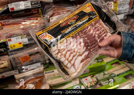 A shopper chooses a package of bacon in a Whole Foods Market supermarket in New York on Monday, April 11, 2022. Citing the Russian invasion of the Ukraine the White House is expecting “extraordinarily elevated” inflation figures on Tuesday as data from the Labor Dept. is released. (© Richard B. Levine) Stock Photo