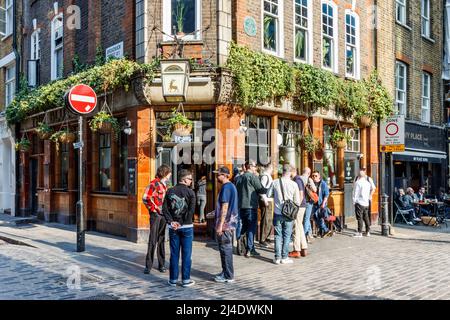 Customers drinking outside the Blue Post pub in Soho as warmer weather arrives in the UK, Broadwick Street, London, UK Stock Photo