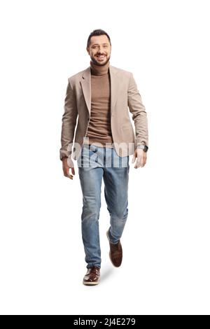 Full length portrait of a young man in a beige suit and jeans walking towards camera isolated on white background Stock Photo