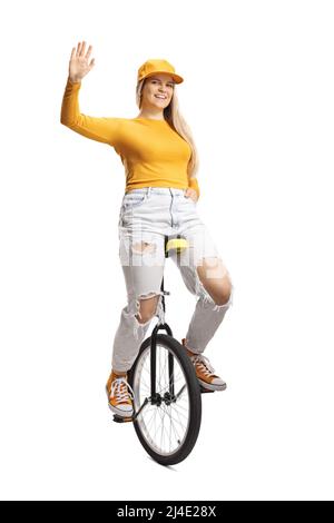 Young female on a unicycle waving at camera isolated on white background Stock Photo