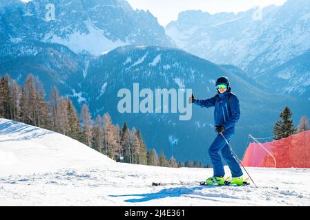 Skier gesturing thumbs up while skiing on landscape against mountains in alps Stock Photo