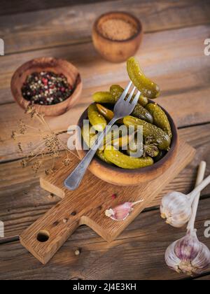 Gherkins, pickled cucumber on a fork, bowl of marinated vegetables  Stock Photo