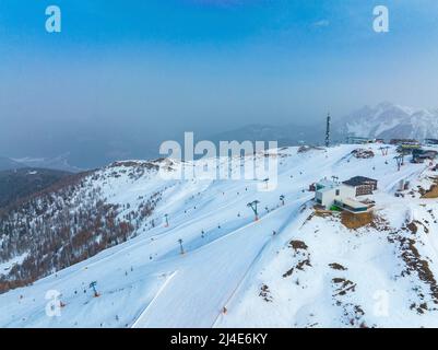 Aerial view of tourist attraction on snow covered mountain against blue sky Stock Photo