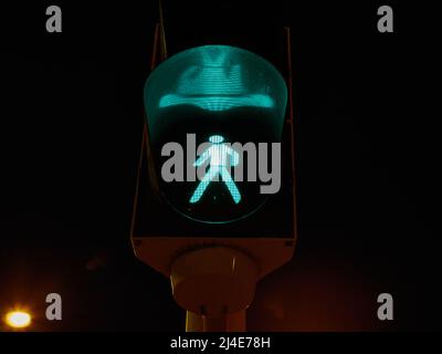 Green pedestrian traffic light glowing at night in Bratislava, Slovakia. Stock Photo
