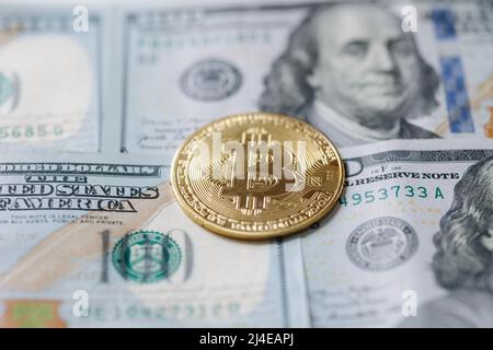 Golden shiny bitcoin crypto currency coins on one hundred US dollar bills. Difference between cryptocurrencies and cash Stock Photo
