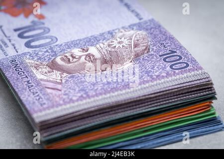 A bundle of Malaysian money, ringits on a gray table top, 100 banknote on top, Economic and business concept Stock Photo