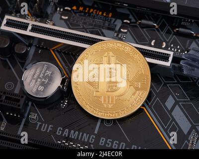 Tambov, Russian Federation - April 10, 2022 A Bitcoin Cryptocurrency lying on a PCI Express slot that is on a TUF Gaming Motherboard. Low key. Close u Stock Photo