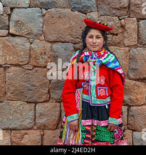 Portrait of young Peruvian indigenous Quechua woman with traditional textile clothing in front of Inca wall in Cusco, Sacred Valley of the Inca, Peru. Stock Photo