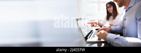 Two Young Businesspeople Analyzing Gantt Chart On Laptop Stock Photo