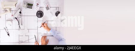 Various Security Equipment In Front Of Two Architects Planning Project On Blueprint Stock Photo