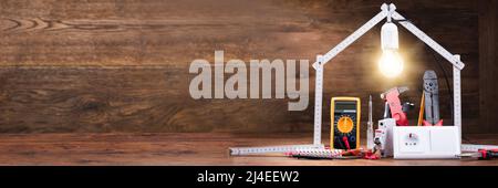 Repair Tools Under The Illuminated House Made With Measuring Tape On The Wooden Table Stock Photo