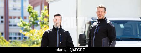 Portrait Of Smiling Two Male Electrician Carrying Tool Boxes Standing Against Truck Looking At Camera Stock Photo