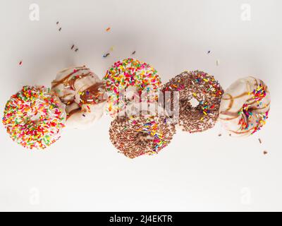 Sweet donuts decorated with chocolate, icing sugar and confectionery sprinkles on a white background. Holiday, birthday, delicious sweet food, lots of Stock Photo