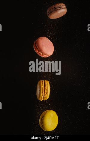Pink and yellow macarons in frozen flight on a black background. Minimalism. There are no people in the photo. There is free space to insert. Restaura Stock Photo
