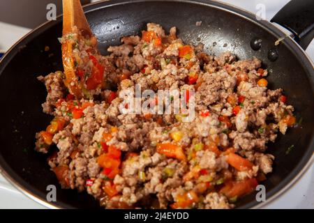 Preparation of ground beef with the traditional Colombian hogao or criollo sauce (salsa criolla) made of onion, tomato, peppers and cilantro Stock Photo