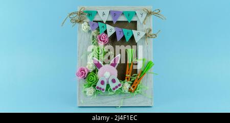 Handmade Creative Easter frame with flowers and cute bunny on blue background Stock Photo