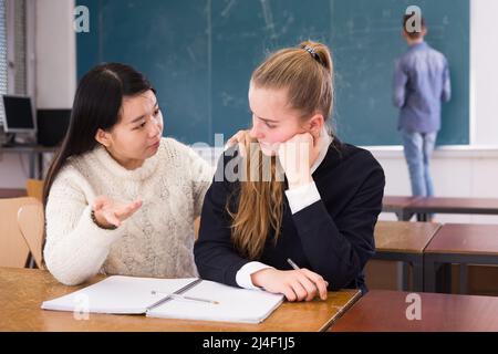 Tired female students during writing notes in classroom Stock Photo