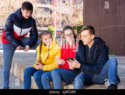 Teenagers are playing on smartphone on street Stock Photo