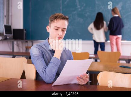 Young thoughtful guy preparing for the exam in classroom Stock Photo