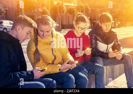 Teenagers absorbed in phones outdoors Stock Photo