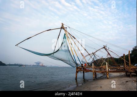 Chinese Fishing nets and small ship at dramatic sunset sky background in Kochi, Kerala, India Stock Photo