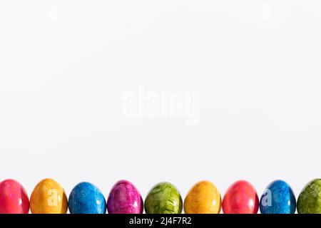 Many Easter eggs arranged in one row on a white background. Easter. Stock Photo